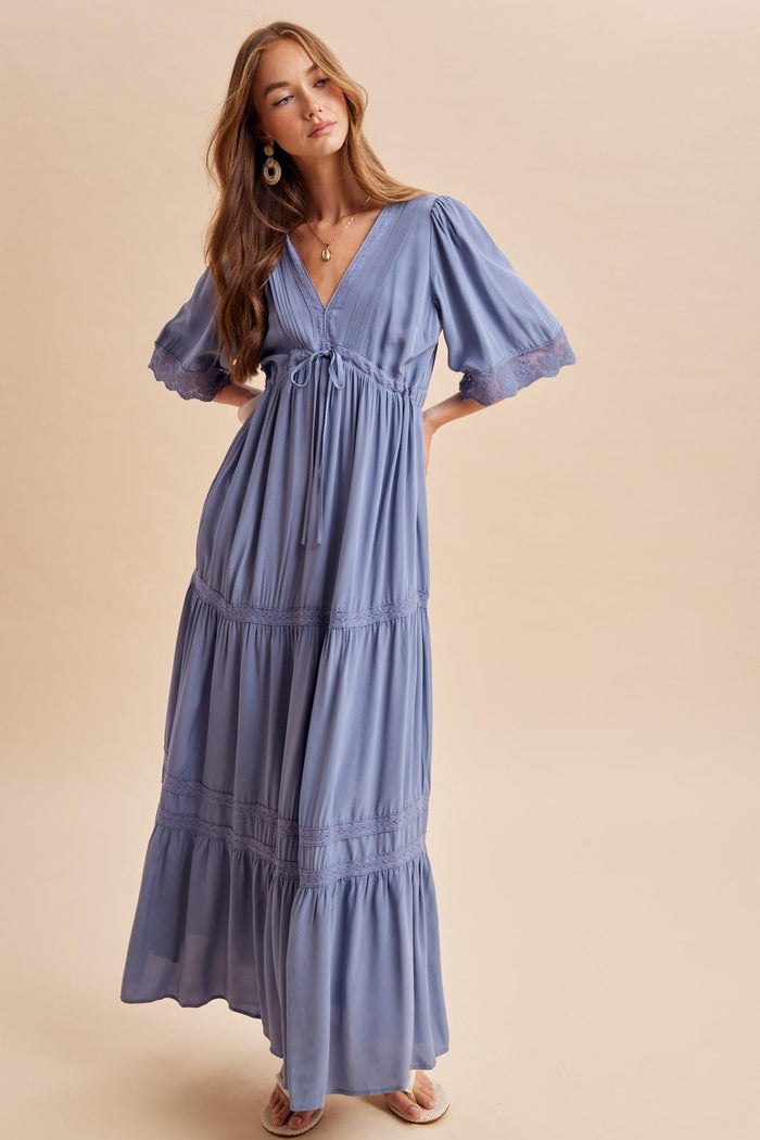 woman wearing a lavender maxi dress with flutter sleeves and a tie waist in a light, flowing fabric