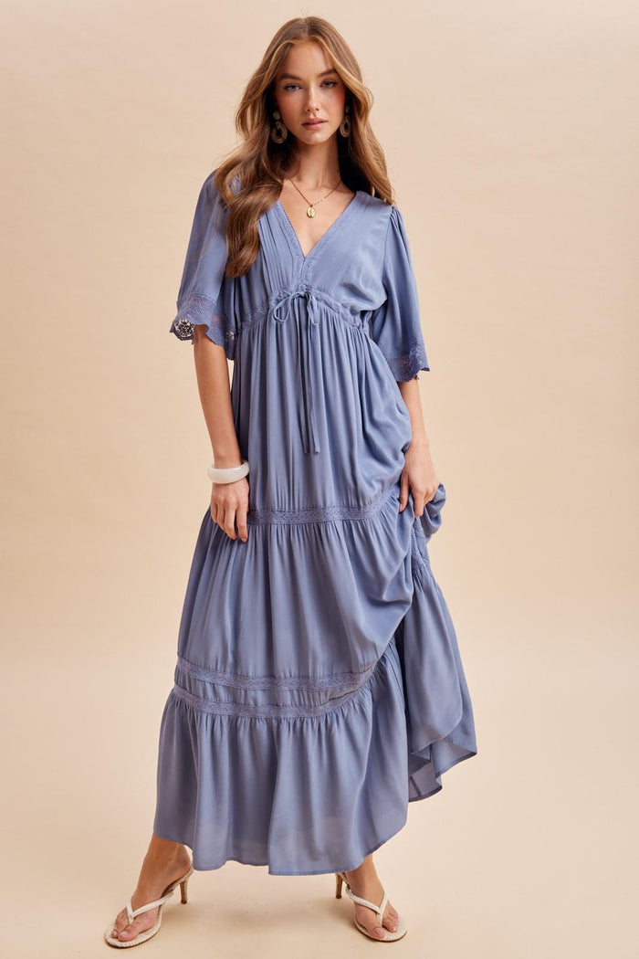 woman wearing a flowy lavender maxi dress with short sleeves and tiered ruffles, styled with strappy sandals