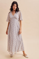 woman wearing a light purple floral maxi dress with short flutter sleeves and a flowy silhouette