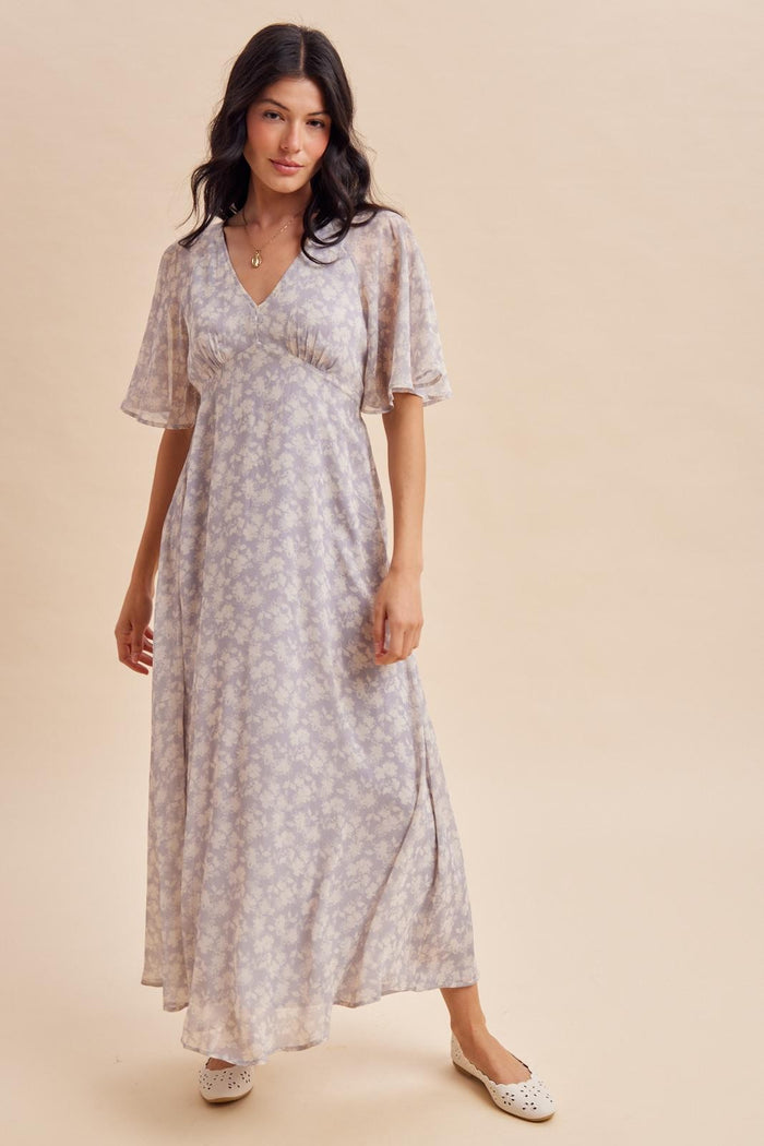 woman wearing a light purple floral maxi dress with short flutter sleeves and a flowy silhouette