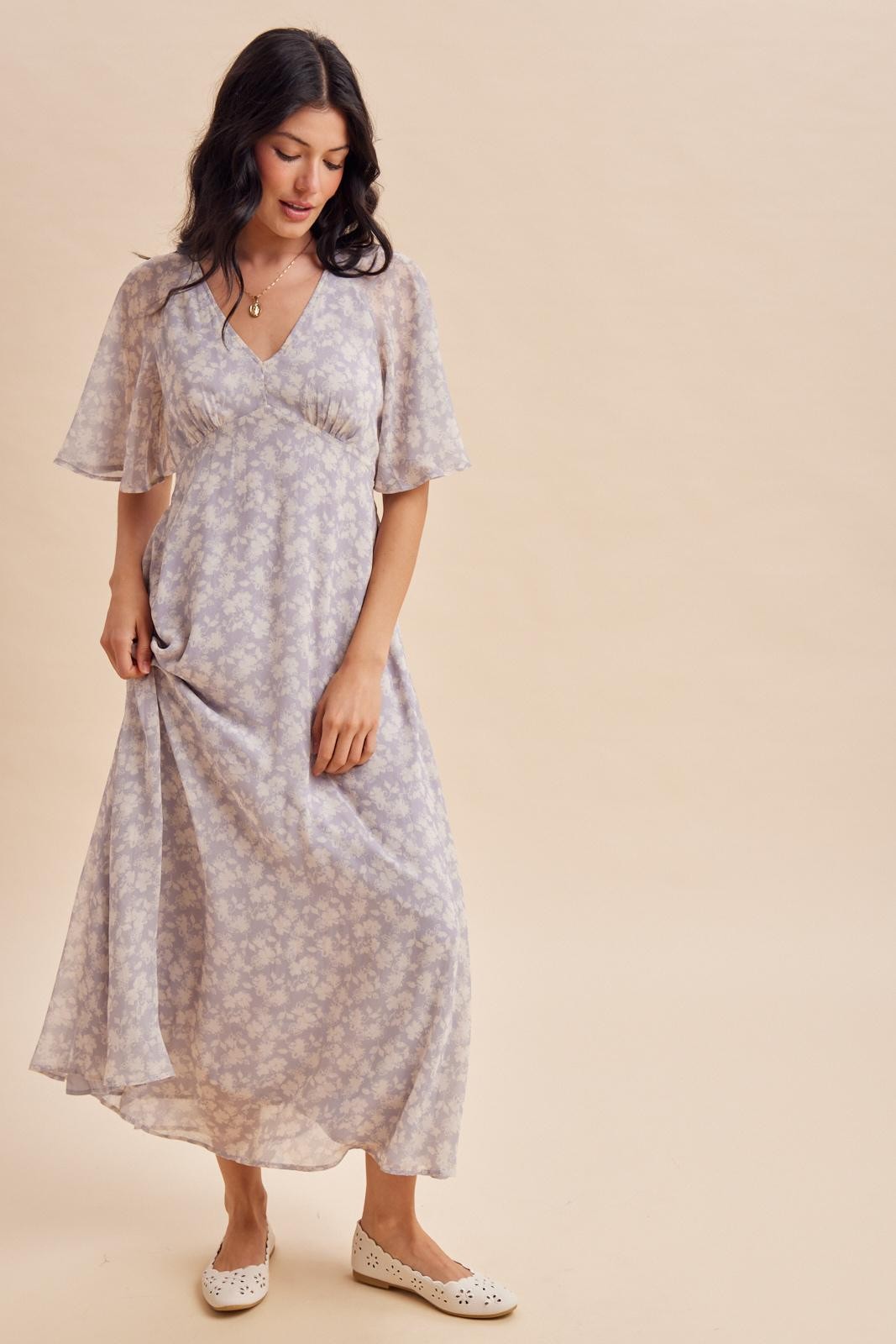 woman wearing a lavender floral maxi dress with flutter sleeves and a v-neckline