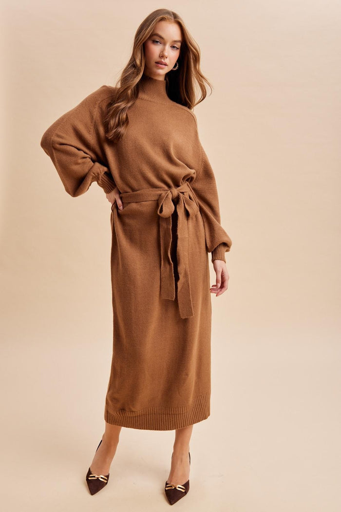 woman wearing a brown long sleeve belted sweater dress with a high neck and ribbed hem