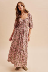 woman wearing a pink floral maxi dress with puff sleeves and a smocked waist standing against a neutral background