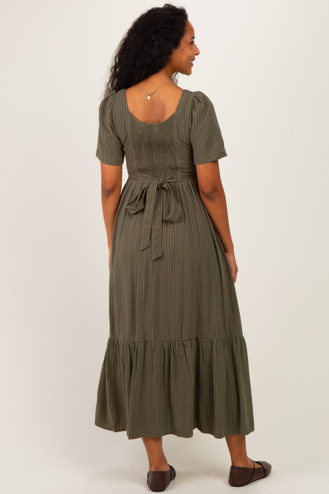 woman wearing a green striped maternity dress with a fitted bodice and a ruffled hem, showing her baby bump from the back