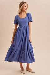 woman wearing a blue striped short sleeve maxi dress with a tiered skirt and a square neckline