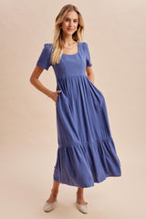 woman wearing a blue ribbed short sleeve midi dress with a square neckline and side pockets