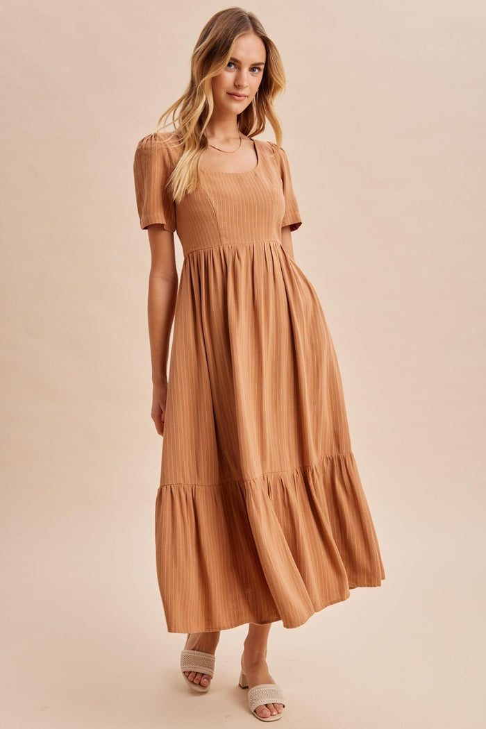 woman wearing a rust-colored short sleeve maxi dress with a square neckline and tiered skirt