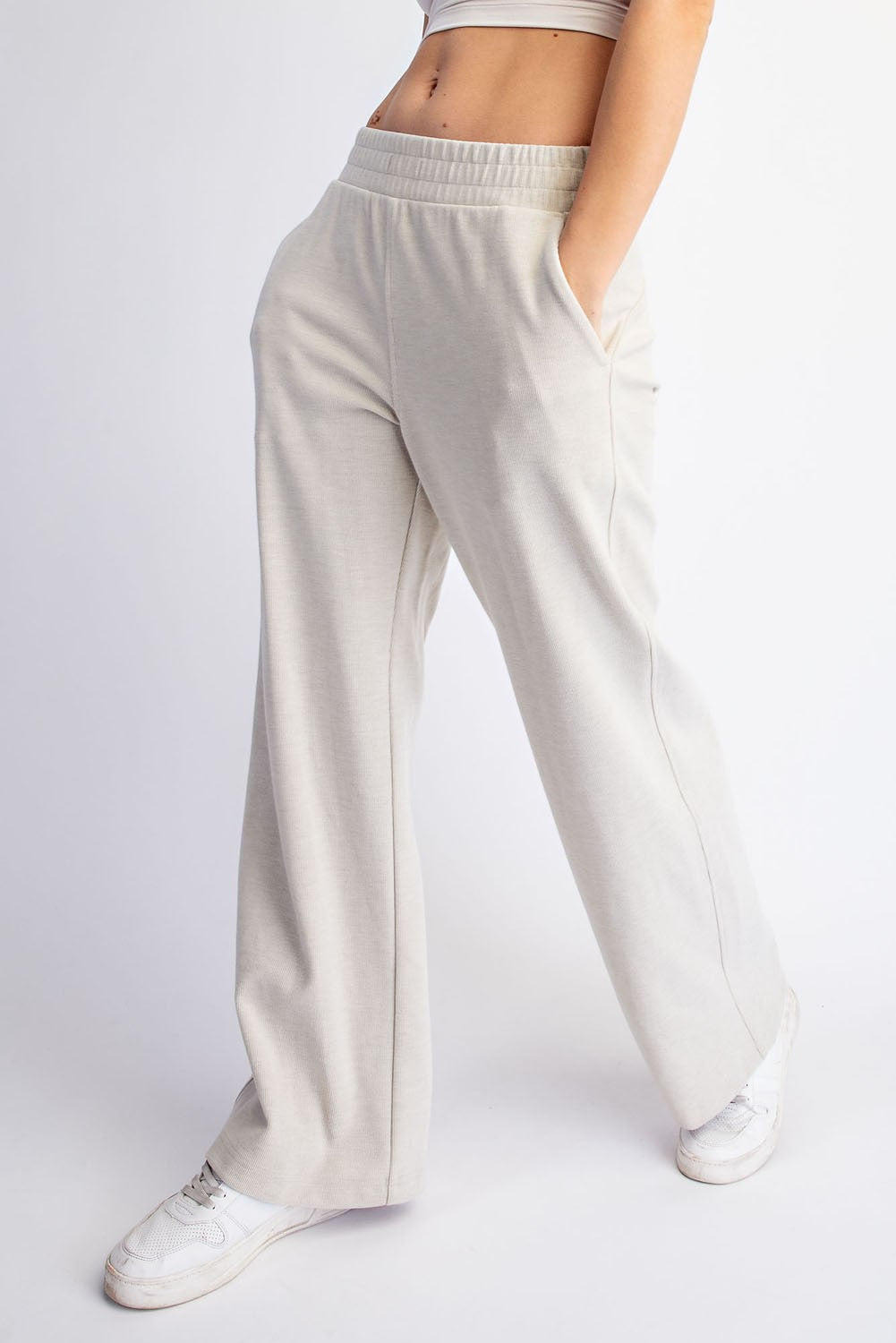 woman wearing light beige wide-leg lounge pants with pockets and an elastic waistband