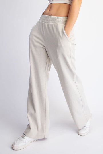 woman wearing light beige wide-leg lounge pants with pockets and an elastic waistband