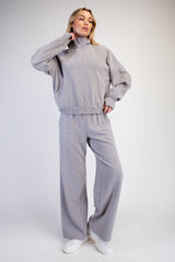 woman wearing a light gray oversized quarter-zip sweatshirt and matching wide-leg sweatpants