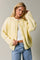 woman wearing a soft yellow button-up cardigan with long sleeves and paired with high-waisted jeans