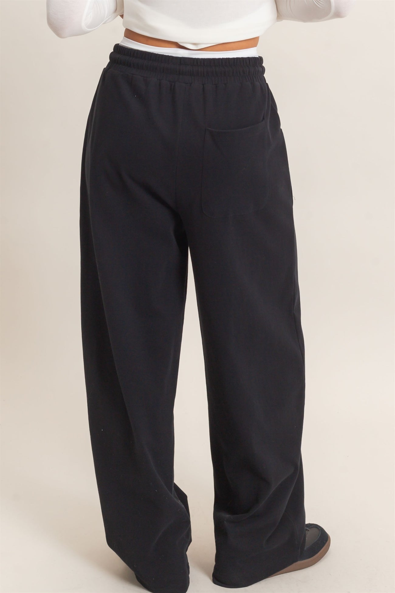 woman wearing black wide-leg sweatpants with a pocket, viewed from the back