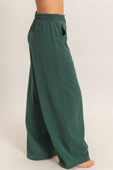 woman wearing green wide-leg pants with an elastic waistband and side pockets