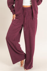 woman wearing burgundy wide leg pants with pockets and a drawstring waist