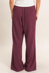woman wearing burgundy wide-leg lounge pants, showcasing a soft ribbed texture from the back