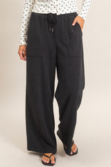 woman wearing black wide-leg lounge pants with side pockets and drawstring waist, styled with a polka dot long sleeve top