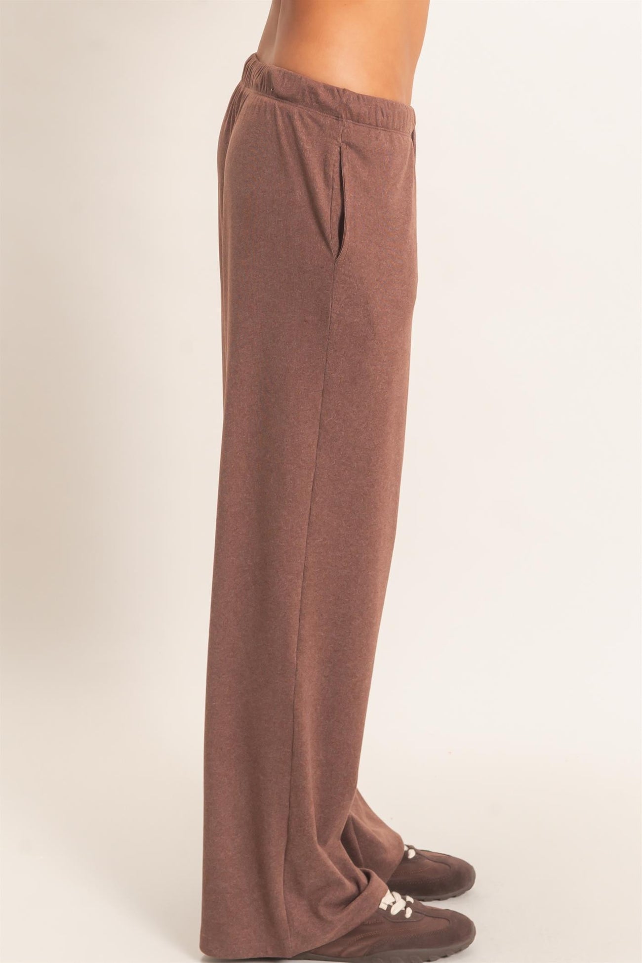 woman wearing brown wide-leg lounge pants with side pockets and an elastic waistband