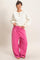 woman wearing a white long sleeve henley top and pink oversized drawstring pants