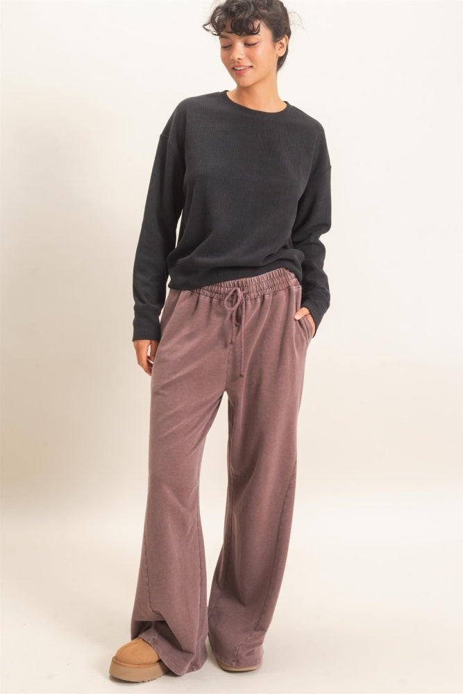 woman wearing a black ribbed sweater and dusty pink wide-leg pants with an elastic waistband and side pockets
