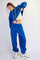 woman wearing a bright blue oversized hoodie and matching joggers, pulling up her hoodie to reveal her midriff