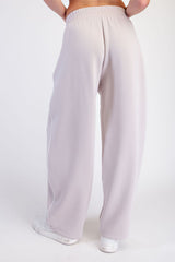 woman wearing light gray wide-leg sweatpants with a high waist and white piping details