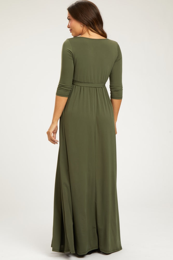 woman wearing an olive green maternity maxi dress with three-quarter sleeves and a cinched waist from the back
