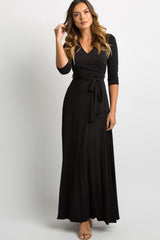 woman wearing a black long sleeve wrap maxi dress with a waist tie against a white background