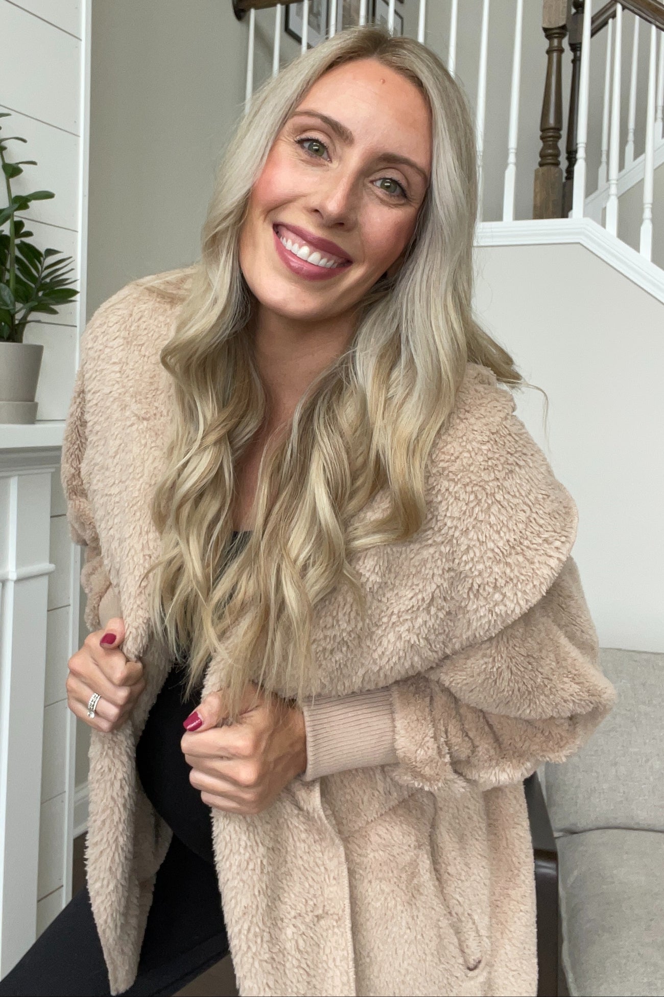 woman wearing a cozy beige oversized teddy coat with a shawl collar and holding her baby bump