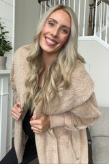 woman wearing a cozy beige oversized teddy coat with a shawl collar and holding her baby bump