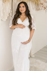 woman wearing a white lace maternity gown and holding her baby bump