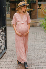 woman wearing a pink floral lace maternity gown and gently cradling her baby bump
