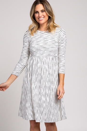 woman wearing a gray and white striped long sleeve dress with a flared skirt and waist seam