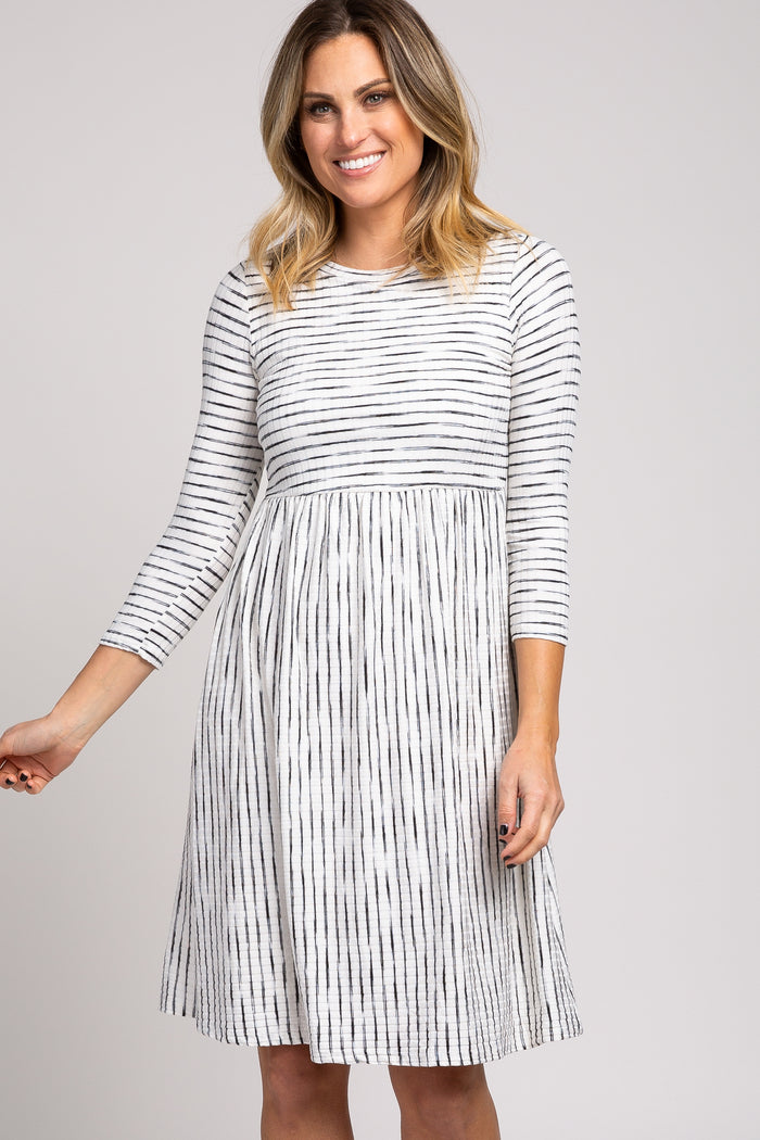 woman wearing a gray and white striped long sleeve dress with a flared skirt and waist seam