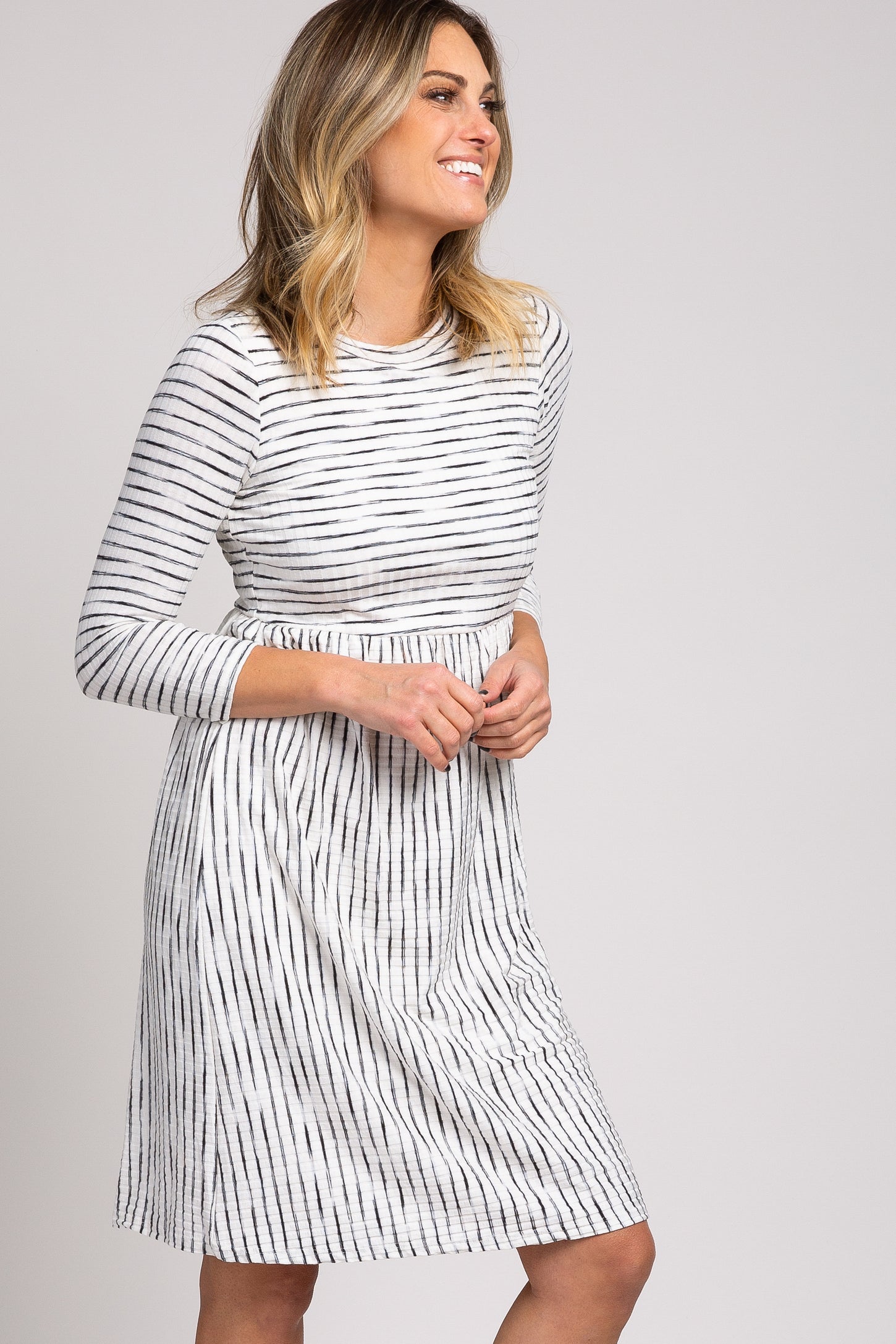 woman wearing a black and white striped long sleeve dress with a fitted bodice and flared skirt