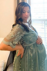 woman wearing a green embroidered maternity dress showcasing her baby bump
