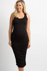woman wearing a black maternity dress, gently hugging her baby bump while standing on a porch