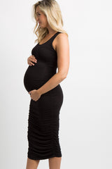 woman wearing a black maternity dress with ruching, showing baby bump while standing outdoors on a porch