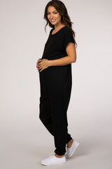 woman wearing a black maternity jumpsuit, showcasing her baby bump with a relaxed fit and short sleeves