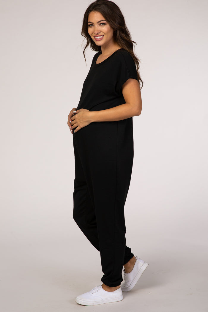 woman wearing a black maternity jumpsuit, showcasing her baby bump with a relaxed fit and short sleeves