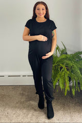 woman wearing a black maternity jumpsuit and holding her baby bump