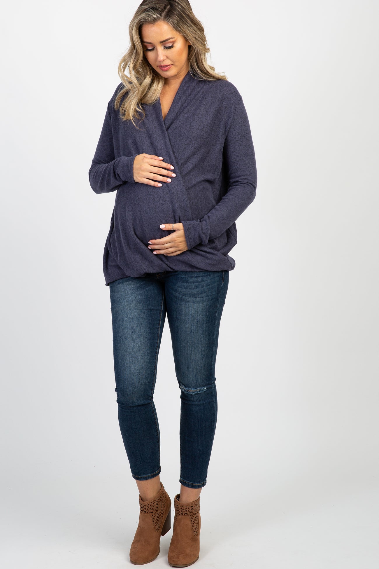 woman wearing a purple long sleeve draped front top and distressed blue skinny jeans