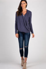 woman wearing a purple long sleeve draped front top and distressed blue skinny jeans