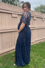 woman wearing a navy blue maternity gown with lace detailing and a visible baby bump