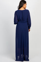 Back view of a woman wearing a long navy blue chiffon maxi dress with long sleeves and a cinched waist
