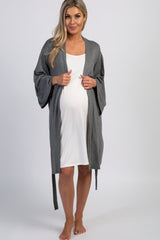 woman wearing a gray maternity robe over a white maternity dress and showing her baby bump