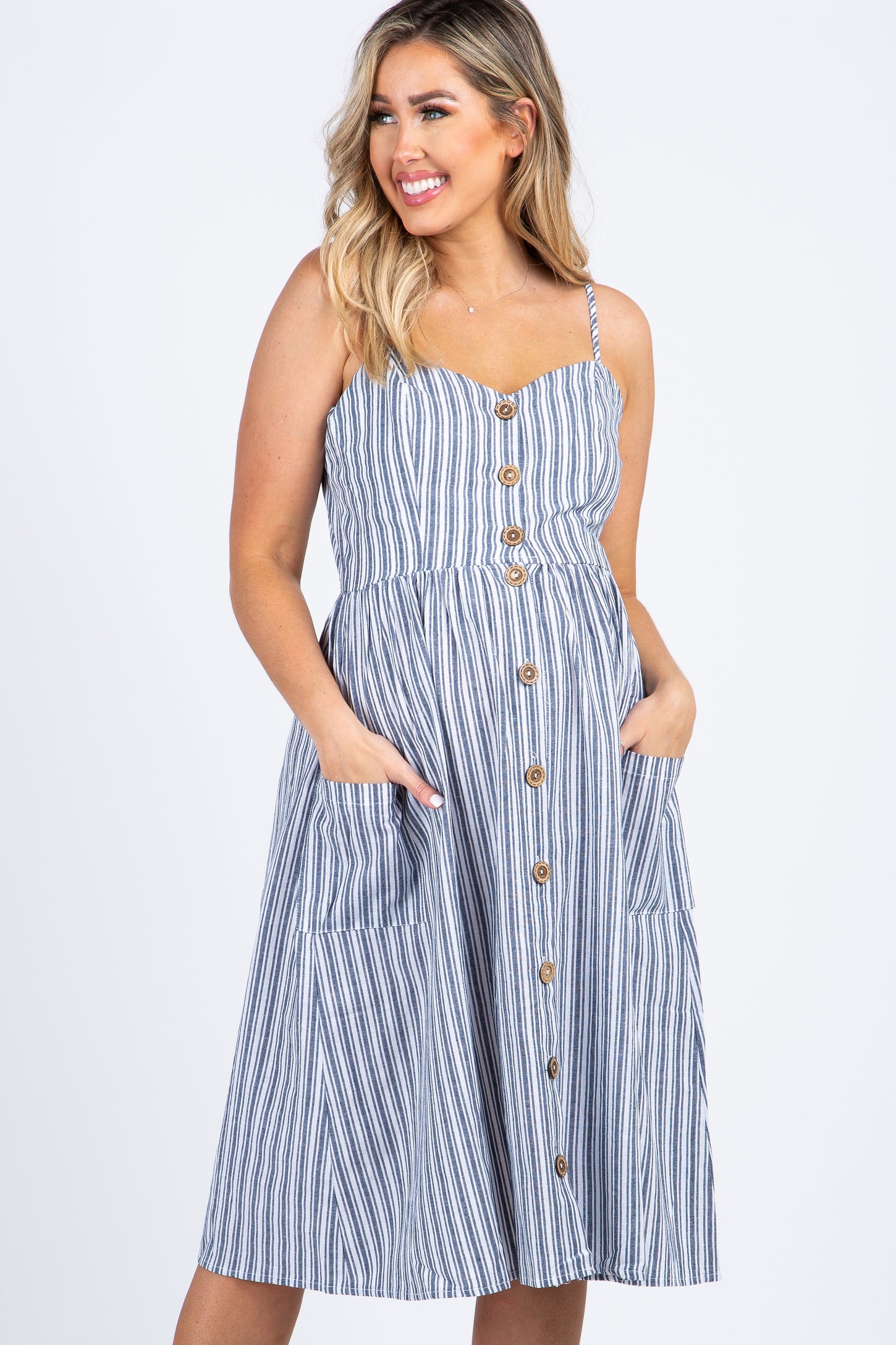woman wearing a blue and white striped midi dress with buttons and pockets against a white background