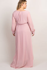 Back view of a woman wearing a long sleeve light pink maxi dress with a belted waist