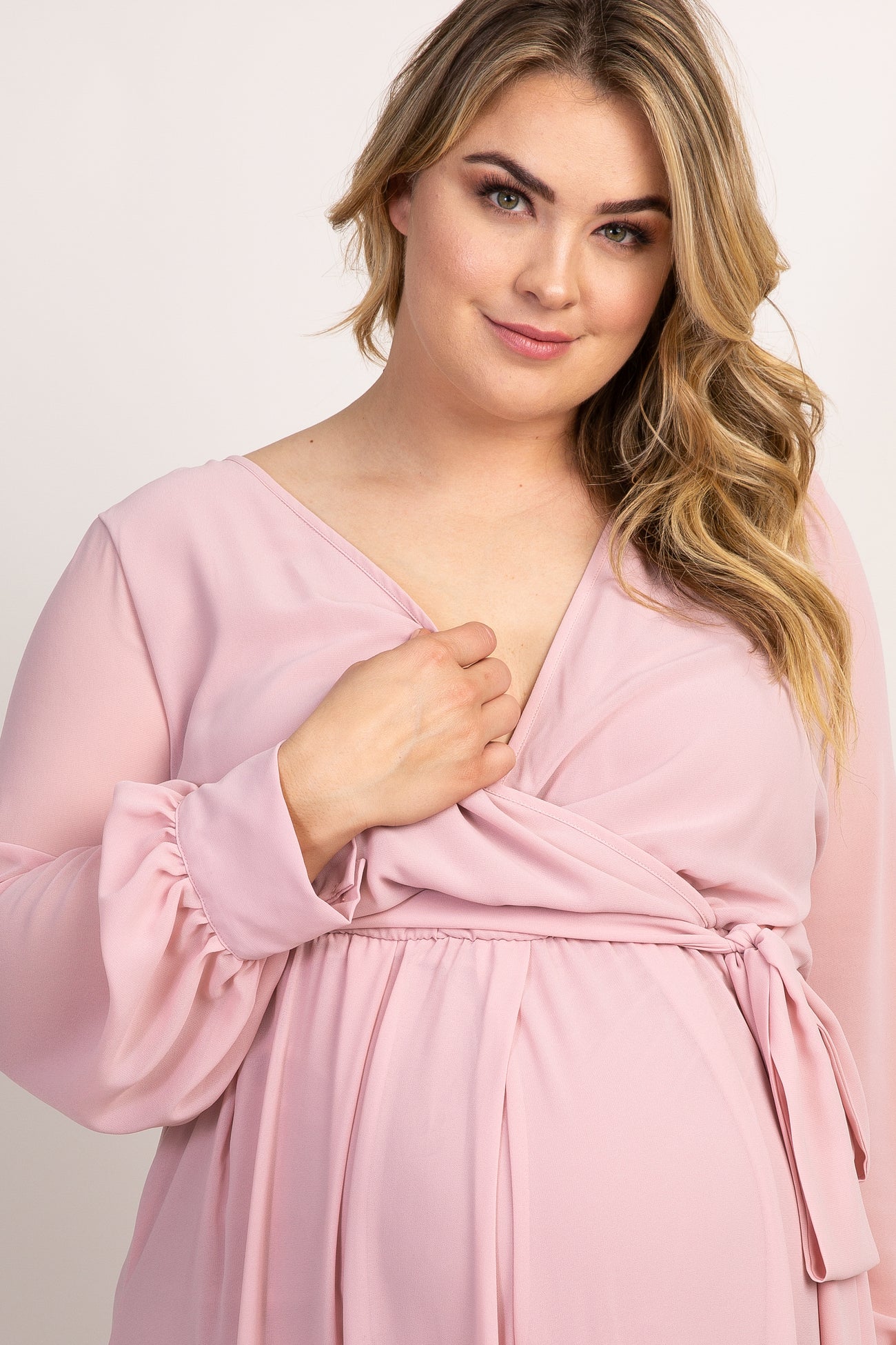 woman wearing a light pink long sleeve wrap maternity dress with a v-neckline