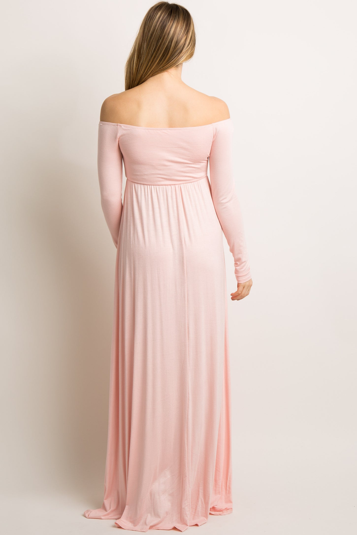 woman wearing a light pink off-shoulder maternity maxi dress, viewed from the back