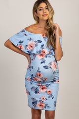 woman wearing a floral off-the-shoulder maternity dress, holding her baby bump